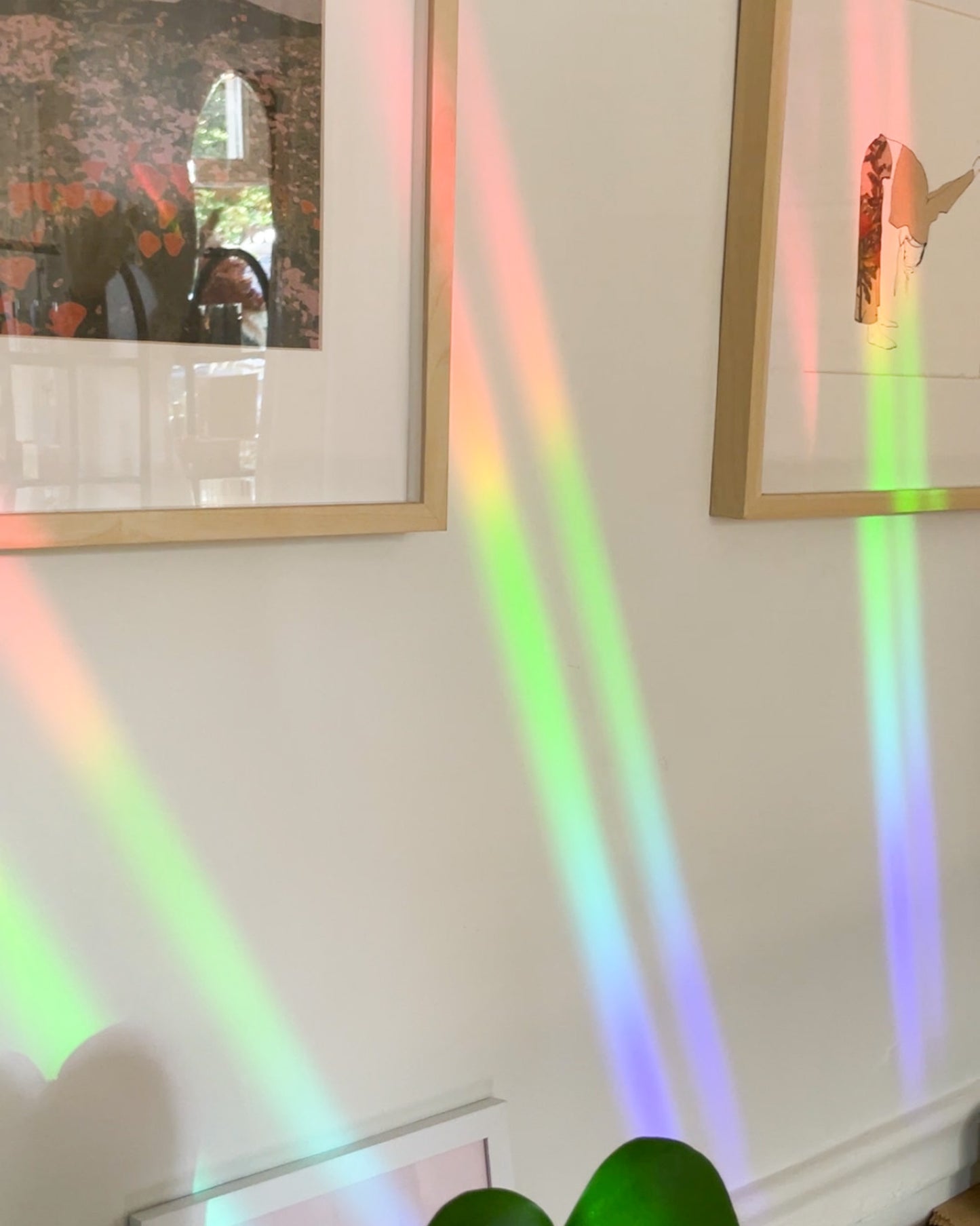Colorful rainbow lights projected on a wall with framed pictures.