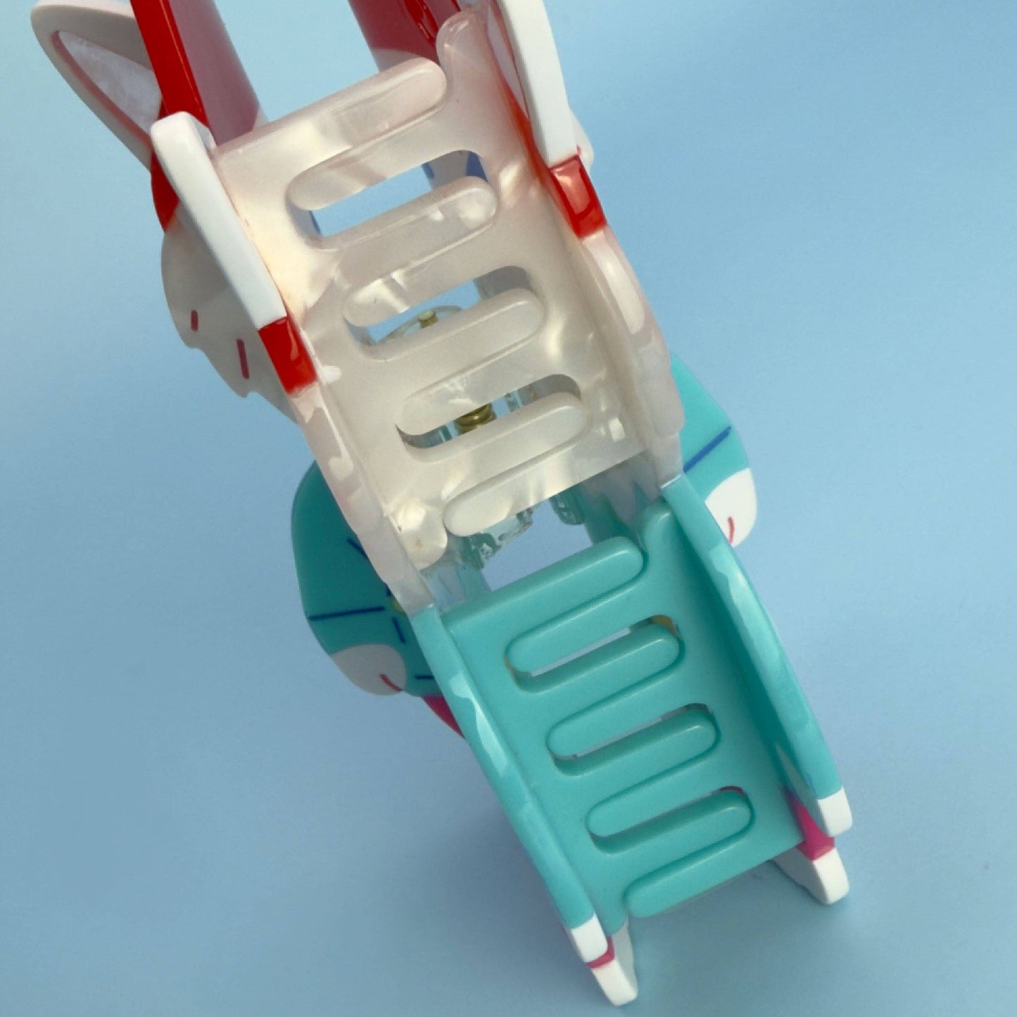 Children's plastic swing with red and white accents on a light blue background