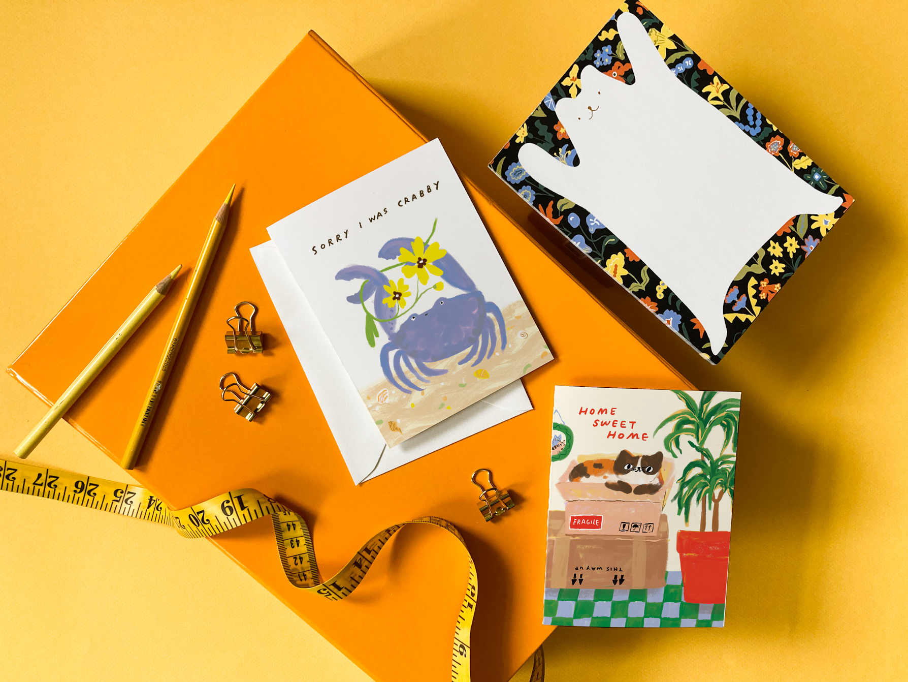 Stationery items including a notebook, card, and stationery on a yellow background