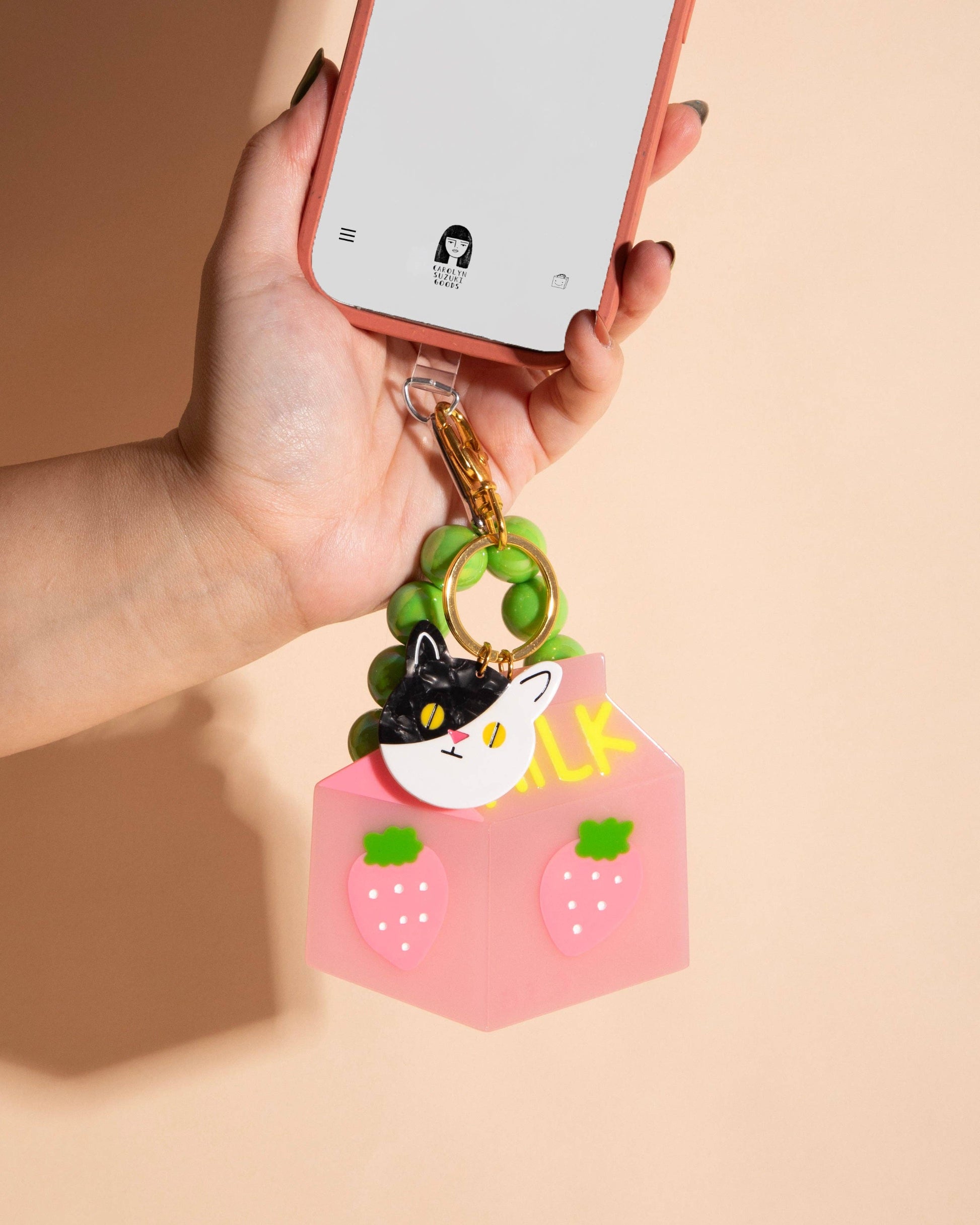 cat charm held by a hand on a beige background