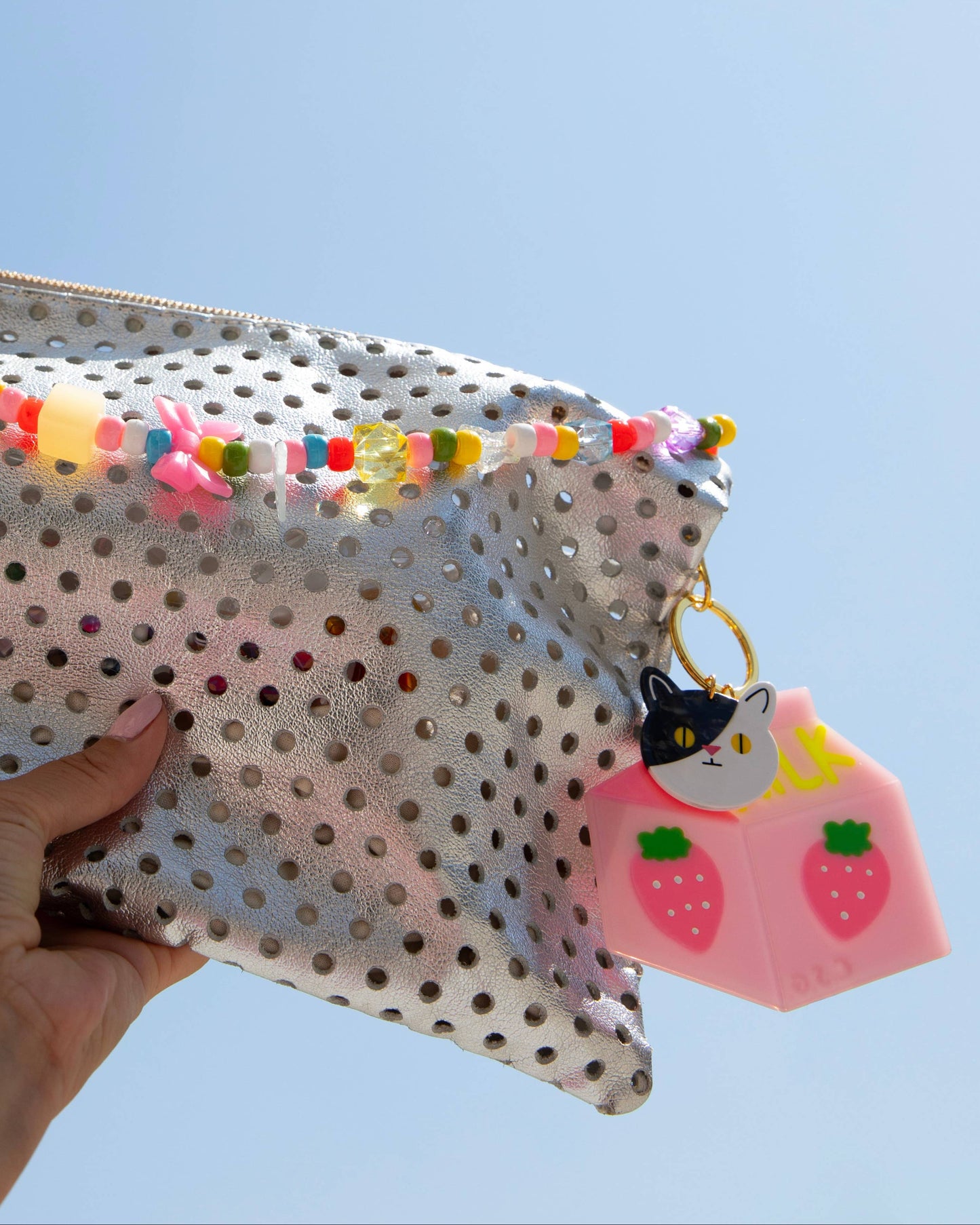 Polka dot pouch with colorful tassels held against a clear blue sky