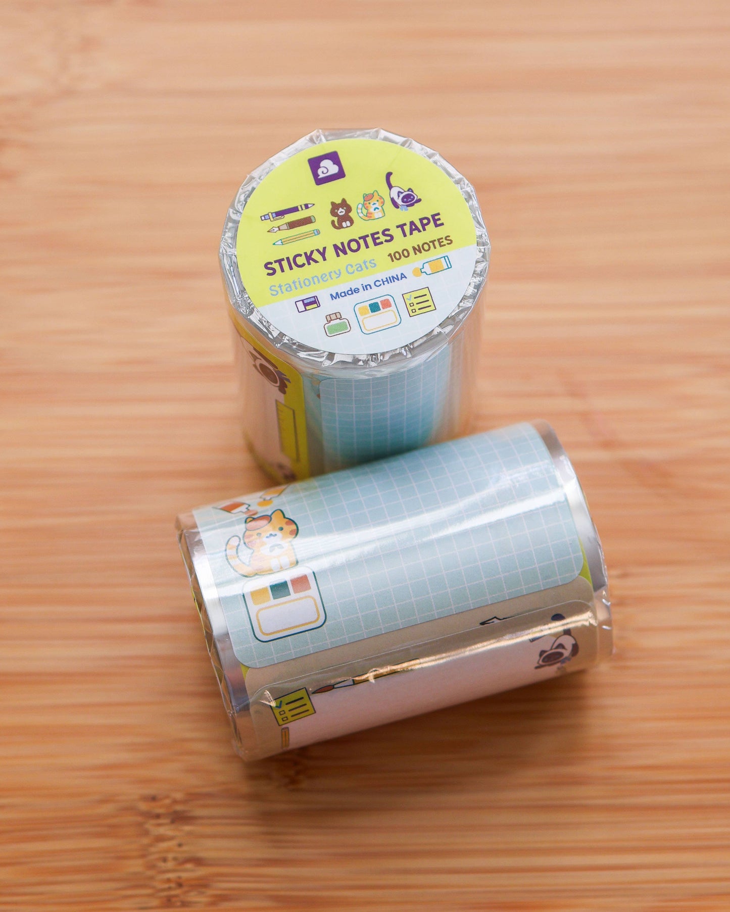 Two rolls of sticky notes tape on a wooden surface