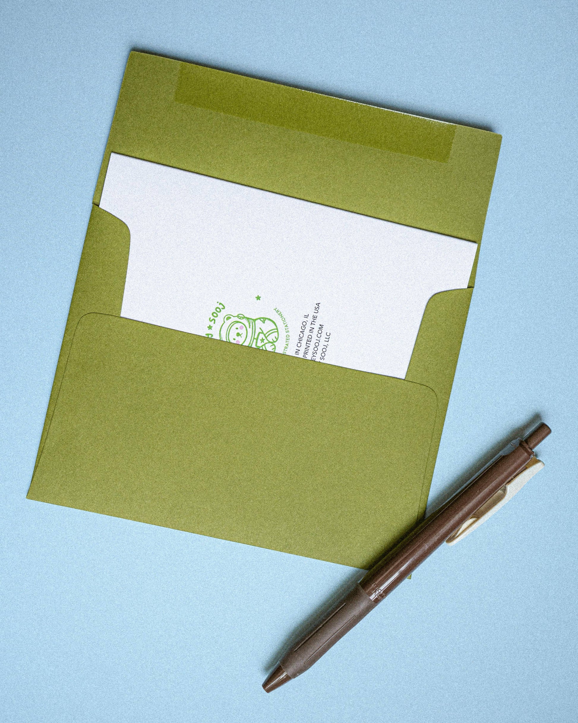 Green envelope with a white card inside on a light blue background