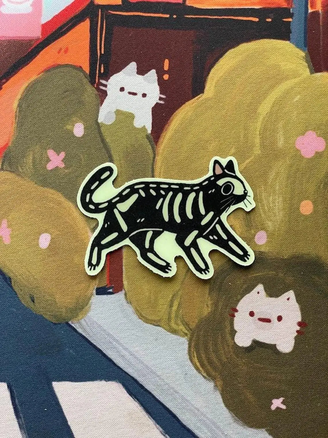 Illustration of a black cat skeleton on fabric with cartoon cats and flowers.