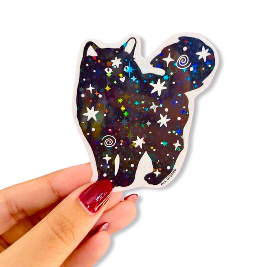 Hand holding a starry night-themed cat silhouette sticker against a white background