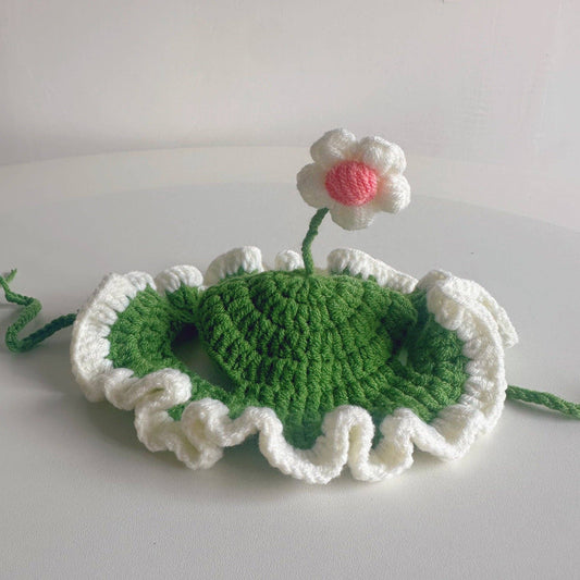 Crocheted green leaf with a white flower on a light gray background