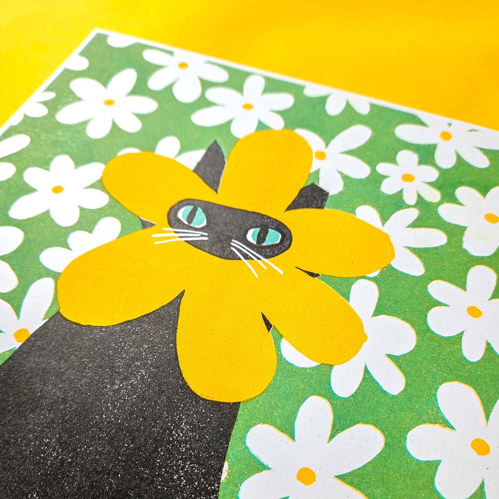 Black cat with yellow flower on a green background with white flowers