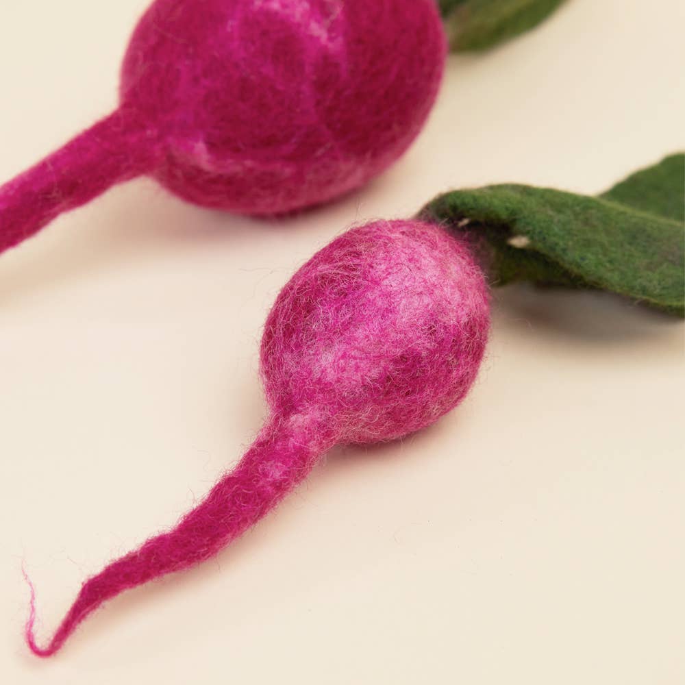 Two pink felted radishes on a beige background